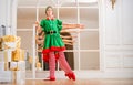 Children dressed in costumes of Christmas elves practice at a ballet bar in front of a mirror in a spacious white studio