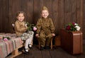 Children are dressed in retro military uniforms sending a soldier to the army, dark wood background, retro style