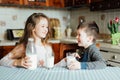 Children drink milk and have fun in the kitchen at the morning. Sister and brother prepare cocoa