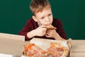 Children eat Italian pizza in the cafe. School boy is eating pizza for lunch. Child unhealthy meal concept. Hungry kids. Pizza re