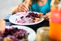 Children eating blueberry strudel with sugar on top.