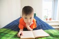 Children education, boy reading book lying on bed, child portrait smiling with book, educational interesting storybook Royalty Free Stock Photo