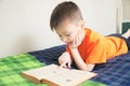 Children education, boy reading book lying on bed, child portrait smiling with book, interesting storybook Royalty Free Stock Photo