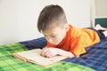 Children education, boy reading book lying on bed, child reading book with interest, educational interesting storybook