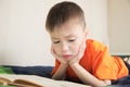 Children education, child reading book lying on bed, boy portrait with book, interesting storybook