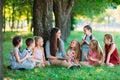 Children and education, young woman at work as educator reading book to boys and girls in park. Royalty Free Stock Photo