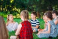 Children and education, young woman at work as educator reading book to boys and girls in park. Royalty Free Stock Photo