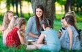 Children and education, young woman at work as educator reading book to boys and girls in park. Royalty Free Stock Photo