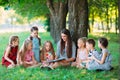 Children and education, young woman at work as educator reading book to boys and girls in park. Royalty Free Stock Photo