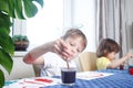 Children engaged in creativity in the home interior. Child draws and colors the picture with paints and a brush