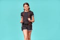 Children engaged in sport. Cute teenage girl in black sportswear with jumping rope looking at camera and smiling while Royalty Free Stock Photo