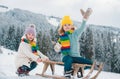 Children enjoying winter, playing with sleigh ride in the winter forest. Kids play with snow. Winter vacation concept Royalty Free Stock Photo