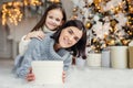 Children, family and celebration concept. Adorable female in knitted sweater holds white present box and small kid stands behind Royalty Free Stock Photo