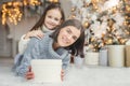 Children, family and celebration concept. Adorable female in knitted sweater holds white present box and small kid stands behind h Royalty Free Stock Photo