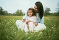 Children, family and field with a mother and girl sitting on grass together outdoor in nature during summer or spring Royalty Free Stock Photo