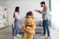 Children and family problems concept. Little girl hiding behind teddy bear, suffering from parents quarrels Royalty Free Stock Photo