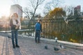 Children feed the birds in the park, little boys and girls feed pigeons, sparrows and ducks in the pond, sunny day in the autumn