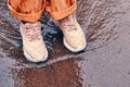 Children feet in orange shoes stand in a spring stream, close-up Royalty Free Stock Photo