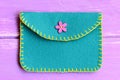 Children felt purse isolated on a wooden background. Purse made of felt using a decorative stitch and decorated with a pink button