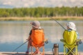 Children with fishing rods sit on a wooden pier and fish Royalty Free Stock Photo