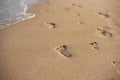 Children footprints in the sand. Human footprints leading away from the viewer. A row of footprints in the sand on a beach in the