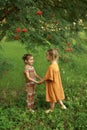 Children in the garden by a tree with rowan berries holding hands looking at each other. Royalty Free Stock Photo