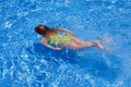 Children gilr swimming underwater in blue pool