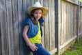 Children girl as kid cowgirl posing on wooden fence