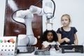 Children girl caucasoid and girl African American education electronic robotic arm on table at class room 