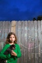 Children girl holding puppy dog on backyard wood fence Royalty Free Stock Photo