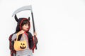 Children girl wearing mysterious Halloween dress holding a scary pumpkin and sickle