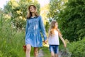 Children girls on forest road holding hands. Sunny summer day, girl holding basket with berries