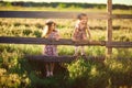 Children, girls in hat sitting on fence in village. walks in countryside