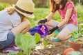 Little beautiful gardeners in gloves with garden shovels watering planted flower