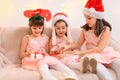 Children girls portrait, sisters dressed in santa helper hat, sitting on a couch in home interior decorated with christmas lights