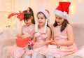 Children girls portrait, sisters dressed in santa helper hat, sitting on a couch in home interior decorated with christmas lights