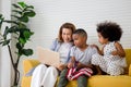 Children and grandmother playing cheerfully in living room, Mother and little children sitting on couch using laptop, boy holding Royalty Free Stock Photo