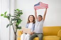 Children and grandmother playing cheerfully in living room, Woman with laptop and kid boy holding USA flag Royalty Free Stock Photo