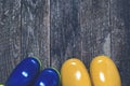 Children gumboots on wooden backround. Top view, copy space. Yellow and blue rain boots for spring or autumn rainy weather