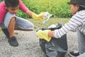Children hand in yellow gloves picking up empty of bottle plastic into bin bag
