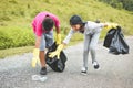 Children hand in yellow gloves picking up empty of bottle plastic into bin bag