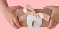 Children hands hold gift box with ribbon bow and heart card tag. Brown kraft paper packaging flat lay. Donation concept Royalty Free Stock Photo