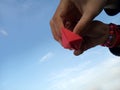 Children hands hold paper ships with blue sky background. Team work and togetherness concept.