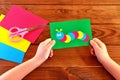 Children hands holding paper applique caterpillar. Paper sheets, scissors on a brown wooden background Royalty Free Stock Photo