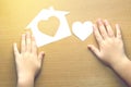 Children hands with small model of house and heart