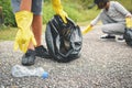 Children hands in yellow gloves picking up empty of bottle plastic into bin bag ,volunteer concept selective and soft focus Royalty Free Stock Photo