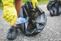Children hands in yellow gloves picking up empty of bottle plastic into bin bag Royalty Free Stock Photo