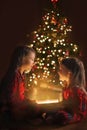 Children happily look at each other opening magic gift boxes at midnight on Christmas eve.
