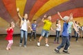 Children have fun dancing under a multi-colored tension dome at a city fair