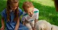 Children have fun with dog on picnic. Cute siblings play with golden retriever. Royalty Free Stock Photo